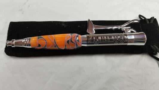 A silver firefighter axe pen with an orange and black flame design on the body, displayed on a black textured surface.
